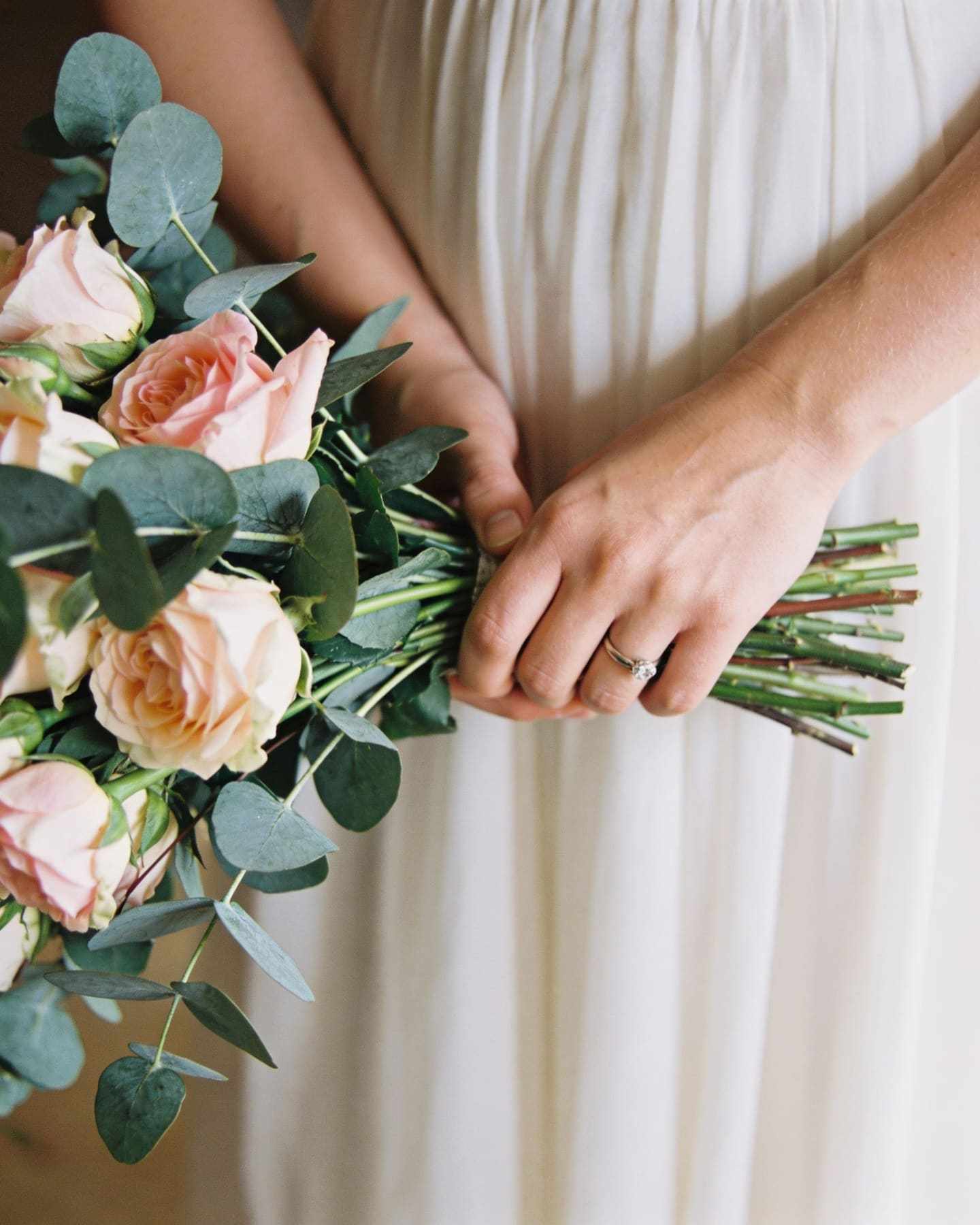 Close-up of the bride's hands holding a bouquet of garden roses and eucalyptus.