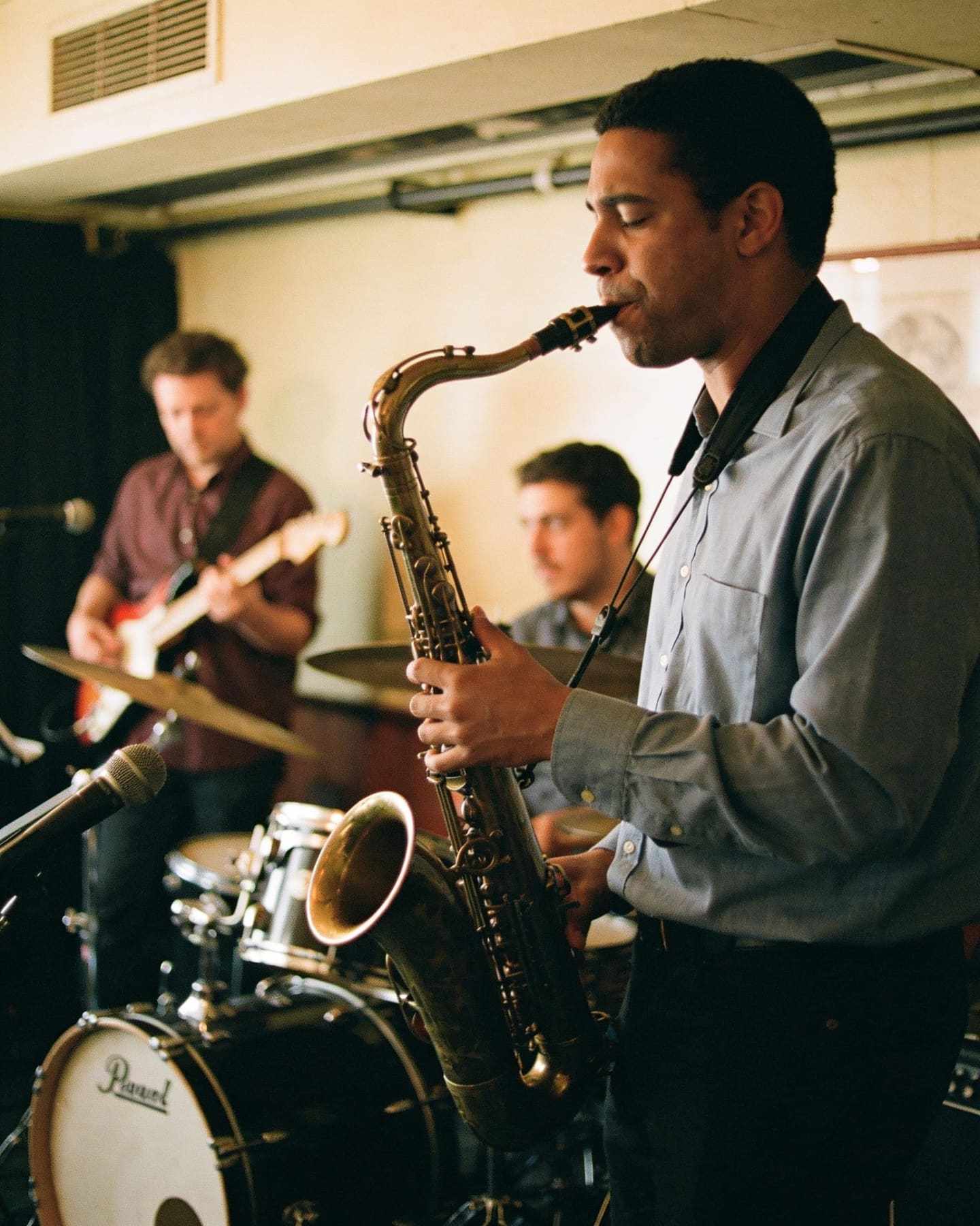 A jazz trio performing in a small venue, the saxophonist mid-solo.